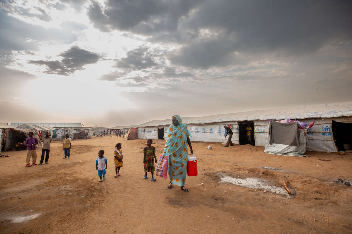 Fairuz stands outside the camp with her grandchildren.