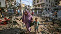 A mother and child walk through the destruction caused by Israeli air strikes in Gaza City.